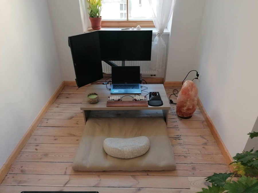 A floor-level workspace with a meditation cushion